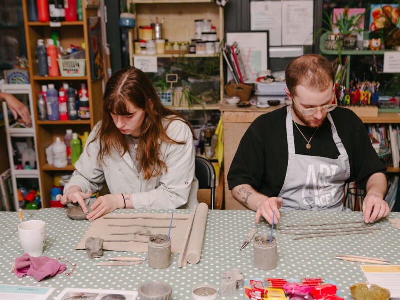 A couple concentrating as they work at a pottery class